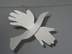 a white paper bird hanging from a string on a gray wall with the word love written below it