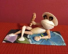 a toy monkey sitting on top of a red bed next to a pink painted wall