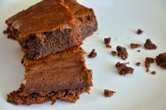 three pieces of chocolate cake on a white plate next to some chopped up brownies