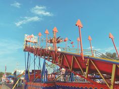 an amusement park ride with red and yellow rides on it's sides, against a blue sky