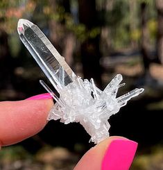 a person holding a small crystal object in their left hand with pink nail polish on it