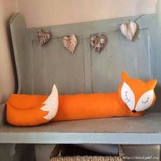 a stuffed fox is sitting on a bench with hearts hanging from the wall behind it