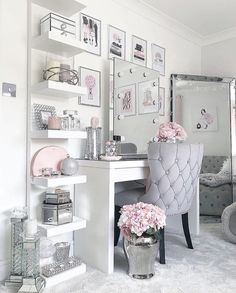 a white desk and chair in a room with pictures on the wall above it, along with pink flowers