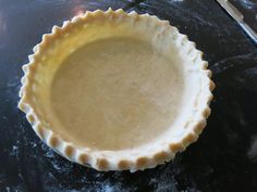 an uncooked pie crust sitting on top of a black table next to a knife