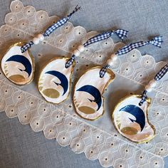 three ornaments are sitting on a doily with blue and white ribbon hanging from them