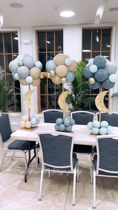 a table set up with blue and gold balloons in the shape of moon on top