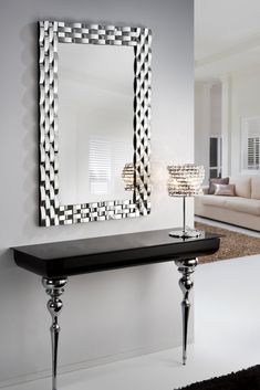 a mirror sitting on top of a wall next to a table with two lamps in front of it