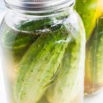 two jars filled with pickles sitting next to each other