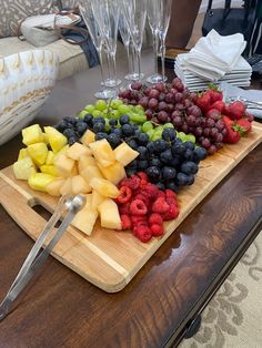 grapes, raspberries, and pineapples are arranged on a cutting board