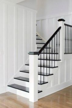 a white staircase with black handrails and wood flooring on the bottom level