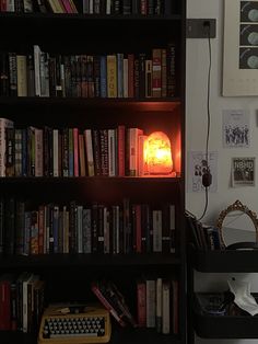 a bookshelf filled with lots of books next to a computer keyboard and lamp