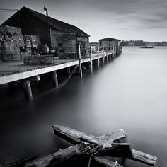 an old wooden dock sitting on top of a body of water next to a building