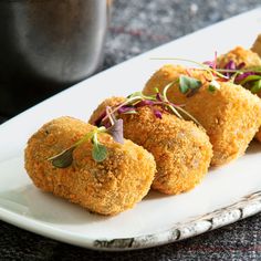 small appetizers are arranged on a plate with garnishes and sprouts