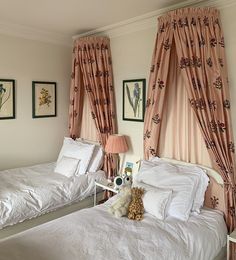 two twin beds in a bedroom with pink curtains