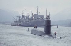 a submarine floating in the water next to another boat