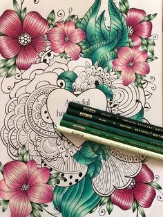 two pencils are sitting on top of an adult coloring book with flowers and leaves