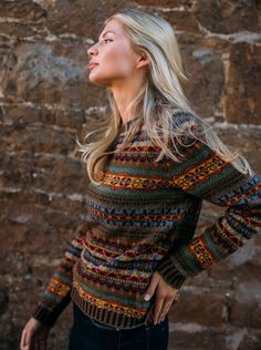 a woman standing in front of a stone wall with her hands on her hips and looking up