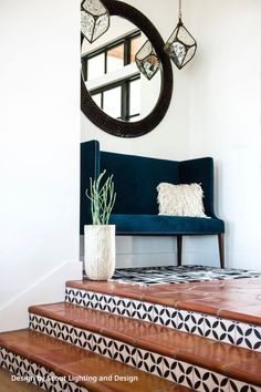 a blue couch sitting on top of a set of stairs next to a round mirror