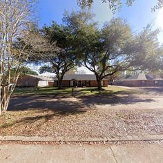 an empty lot with trees and houses in the background