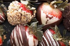 chocolate covered strawberries are arranged in a row on a tray with leaves and sprinkles