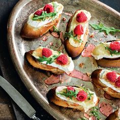 a platter filled with toasted bread topped with raspberries