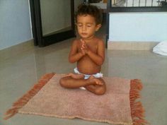 a little boy sitting on the floor with his hands folded in front of him and saying, become as little children