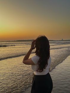 a woman standing on top of a beach next to the ocean