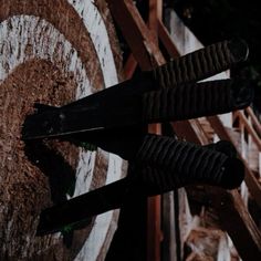 two pairs of scissors sitting on top of a piece of wood next to a target