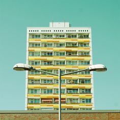 an apartment building with multiple balconies and windows on the top floor, against a blue sky