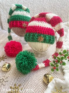 two knitted hats sitting on top of a table next to bells and christmas decorations