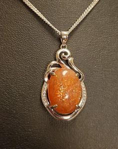 "Sparkling Natural Sunstone Necklace, 13x17mm Orange Schiller Stone, 925 Sterling Silver Swirl Top Pendant With Tiny Cubic Zirconia Trim. 20\" Sterling Chain. Chain Length Options Available By Messaging Seller At Time Of Purchase. Gift Box Included." Luxury Orange Faceted Necklace, Orange Gem Necklace, Sunstone Necklace Pendants, Luxury Orange Necklace With Natural Stones, Orange Stone Necklace, Magic Amulet Necklace, Gem Necklace Stones, Silver Oval Necklace With Sparkling Stones, Oval Necklace With Sparkling Stones For Gift