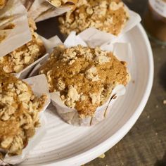 several muffins on a plate with paper wrappers