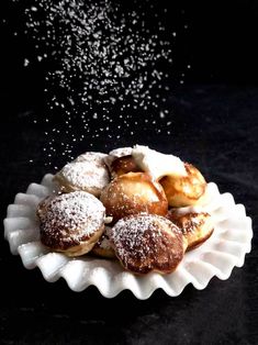 powdered sugar sprinkled on top of pastries in a white dish with black background