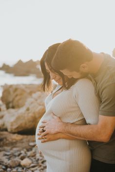 a pregnant couple embracing on the beach