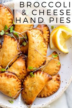 broccoli and cheese hand pies on a white plate with lemon wedges