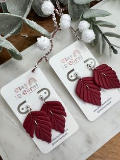 two red leaf shaped earrings are on display