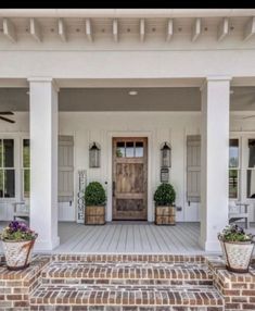 a front porch with potted plants on the steps and an entry way leading up to it