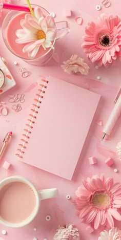 a pink desk topped with lots of flowers and notebooks next to a cup of coffee