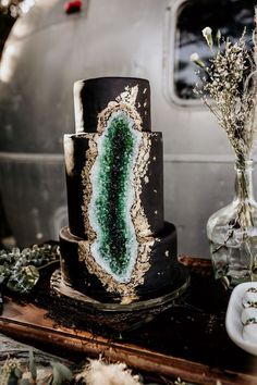 a three tiered cake with green and black frosting on it's side