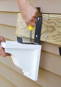 a man is using a drill to fix a house siding gap on the side of a house