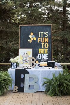 an outdoor birthday party is set up on the deck with decorations and signs that read it's fun to be one