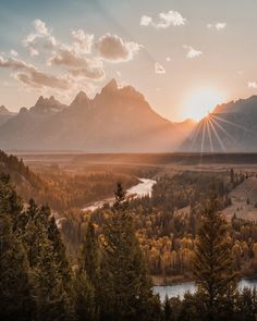 the sun is setting over a valley with trees and mountains in the background, as seen from an overlook point