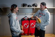 two young men standing next to each other in front of baseball caps and jersey shirts