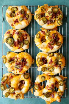 there are many bagels with cheese and pickle toppings on the top one is sitting on a cooling rack