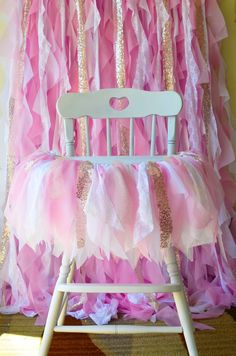 a chair with pink and gold ruffles on the back, sitting in front of a backdrop