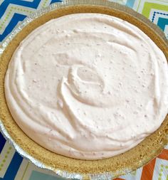 a pie with white frosting sitting on top of a colorful table cloth next to a fork