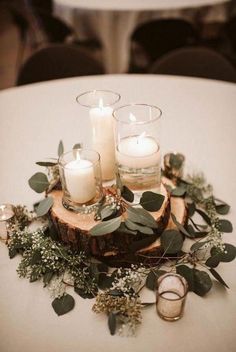 some candles are sitting on a table with greenery