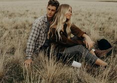 a man and woman are sitting in the tall grass