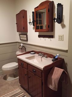 a bathroom with a sink, toilet and wooden cabinetry on the wall above it