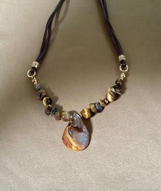 I love natural stones with their beautiful colors. This necklace is made with brown Tigereye  beads and stone chips with a brown shell nugget as a centerpiece. I have added small gold beads and attached it to brown satin cord. It is finished with a gold lobster claw clasp and a 2 inch extender chain. The length is 16 inches but can be lengthened with the 2 inch extender cord. This can be worn with both a casual or dressy outfit. Matching  earrings are available.. Adjustable Brown Teardrop Jewelry, Nature-inspired Brown Jewelry With Gemstone Beads, Beaded Teardrop Brown Necklace, Adjustable Brown Beaded Necklaces With Stones, Adjustable Brown Beaded Necklace With Stones, Brown Beaded Teardrop Necklace, Brown Beaded Necklaces With Stones, Brown Beaded Healing Jewelry, Spiritual Brown Agate Beaded Necklaces